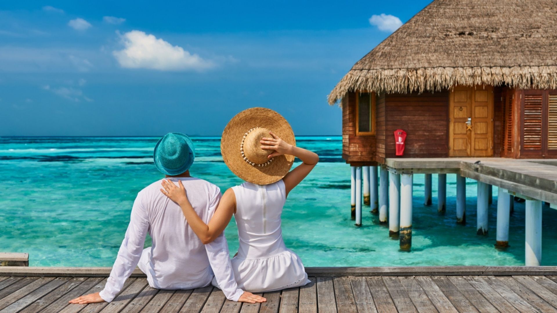 Couple on a tropical beach jetty near water villa at Maldives